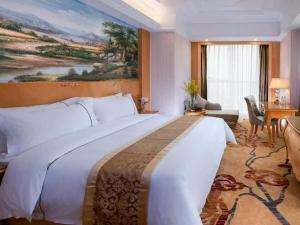 Vienna International Hotel Foshan Lecong Center في شوند: غرفه فندقيه سرير كبير ولوحه كبيره