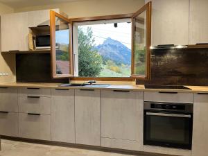 a kitchen with a view of a mountain from a window at Le Chal'heureux , grand chalet familial 8 personnes in Saint-Pierre-de-Chartreuse