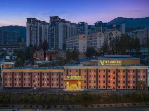 a building with a sign on it in front of a city at Vienna International Hotel Kunming longquan road Finance University in Kunming