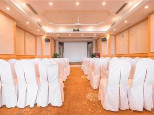 um quarto com filas de cadeiras brancas num quarto em Vienna International Hotel Shenzhen Xiashuijing Metro Station em Shenzhen