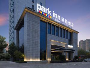 a building with a sign on top of it at Park Inn by Radisson Hanzhong Central Square & High speed rail station in Hanzhong