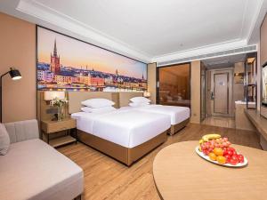 a hotel room with two beds and a table with a plate of fruit at Vienna International Hotel Xianyang International Airport Hotel in Xianyang