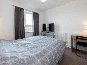 Dormitorio con cama, escritorio y TV en Pass the Keys Free Parking and Walking Distance Etihad Coop Arena en Mánchester