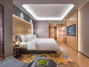 een grote slaapkamer met een groot bed en een bank bij Park Inn by Radisson Tongling The City Core in Tongling