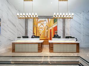 twee mannen zitten aan een bureau in een kamer met een schilderij bij Vienna International Hotel Chengdu Shuangliu Airport Terminal Beijing Hualian in Chengdu