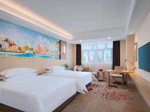 Vienna International Hotel FuJian PuTian Pearl في بوتيان: غرفة فندقية بسريرين ولوحة على الحائط