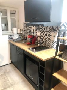 eine Küche mit schwarzen Schränken und einer Arbeitsplatte in der Unterkunft Sainte Cécile 9 - Studio Pop entre sol in Vichy