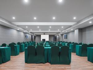 a conference room with green chairs and a screen at Park Inn by Radisson Hanzhong Central Square & High speed rail station in Hanzhong