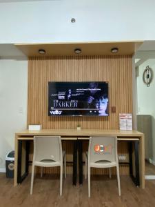 a table with two chairs and a television on a wall at JC SpaceRentals 127B Amani Grand Resort Residences, balcony pool view, Ground floor, 5 mins frm airport, free wifi, Netflix in Pusok