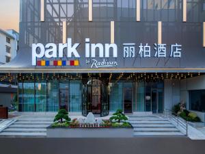 Park Inn by Radisson Shaoxing China Keqiao في شاوكسينج: مبنى أمامه علامة شركة حديقة