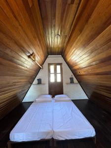uma cama grande num quarto de madeira com uma janela em Chalé em Bombinhas/Porto belo em Porto Belo