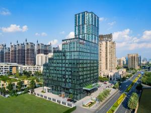 a tall glass building in the middle of a city at Park Inn by Radisson Chengdu Sihe Metro Station Xinchuan in Chengdu