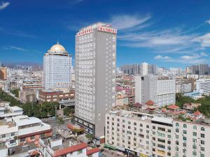a tall building in a city with buildings at Vienna International Hotel FuJian PuTian Pearl in Putian