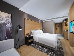a bedroom with a large white bed and a couch at Park Inn by Radisson Tianjin Five Old Street Nanjing Road in Tianjin