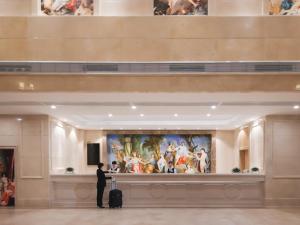 un homme avec une valise qui regarde un tableau dans un musée dans l'établissement Vienna International Hotel FuJian PuTian Pearl, à Putian