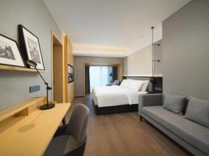 a hotel room with a bed and a couch at Park Inn by Radisson Chengdu FengHuang Mountain Sports Park in Xindu +25 photos