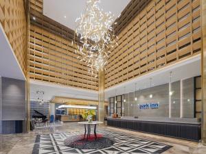a lobby with a table and a chandelier at Park Inn by Radisson Tianjin Jinghai Wanda Plaza in Jinghai