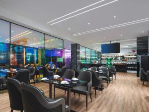 a restaurant with tables and chairs and a tv at Park Inn by Radisson Hanzhong Central Square & High speed rail station in Hanzhong