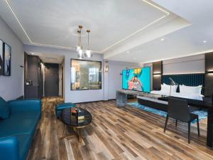 a hotel room with a large bed and a blue couch at Park Inn by Radisson Hanzhong Central Square & High speed rail station in Hanzhong