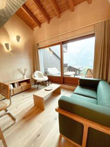 a living room with a green couch and a large window at Chalet Mélèze skis aux pieds Alpes, Sainte-Foy station 1550 in Sainte-Foy-Tarentaise
