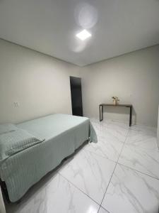 a bedroom with a bed and a table on a tiled floor at Casa com piscina in Bonito