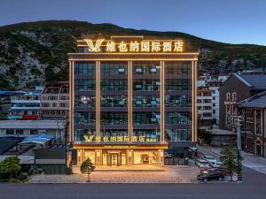 un grand bâtiment avec un panneau en haut dans l'établissement Vienna International Hotel Wudu Gujinli Longnan, à Longnan