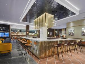 a lobby with a bar with stools and a restaurant at Park Inn by Radisson Nanchong Yilong Star City Plaza in Yilong