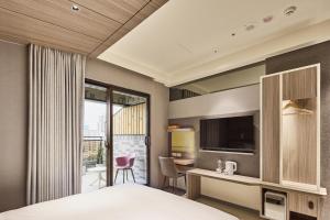 a hotel room with a bed and a desk and a tv at Orange Hotel -Hanzhong, Taipei in Taipei