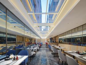 a restaurant with tables and chairs and a ceiling with skylights at Park Inn by Radisson Tianjin Five Old Street Nanjing Road in Tianjin