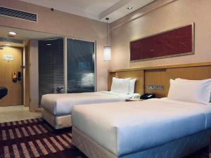 um quarto de hotel com duas camas e uma televisão em Park Inn by Radisson Shanghai Downtown em Xangai