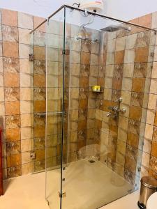 a shower with a glass door in a bathroom at Dandelion By The Hills in Lakhwār
