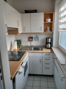 eine kleine Küche mit weißen Schränken und einem Waschbecken in der Unterkunft Ferienwohnung Möwenschiss - Haus Bake in Büsum