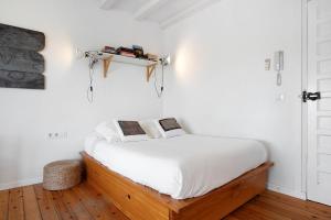 una camera da letto con letto, lenzuola bianche e pavimenti in legno di Varadero Beach Penthouse a Los Caños de Meca