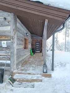 un porche de una cabaña de madera en la nieve en Mäntyharju-mökki, en Syöte