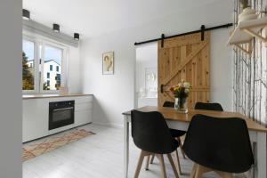 a kitchen with a wooden table and black chairs at Elite Apartments Cozy Studio Sopot in Sopot