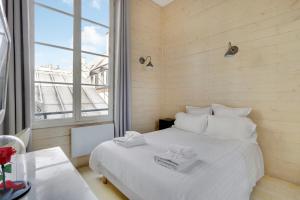 ein Schlafzimmer mit einem weißen Bett und einem großen Fenster in der Unterkunft Paris Marais Best WE MERRIS in Paris