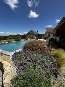 una piscina con flores púrpuras junto a una casa en Un grand Paradis dans le Périgord en Saint-Amand-de-Coly