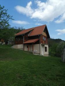 a large house with a grassy field in front of it at Apartman Panorama in Mokra Gora