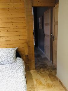 ein Schlafzimmer mit einem Bett und einer Holzwand in der Unterkunft Le Séchoir un Grand coin de paradis in Saint-Amand-de-Coly