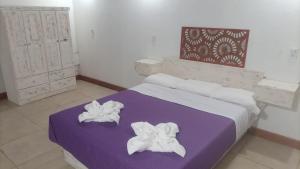 - une chambre avec un lit violet et des serviettes dans l'établissement POSADA DE LA LUNA, à Luján de Cuyo
