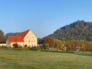 a large white house with a red roof in a field at Landhaus Böhmer, Ferienhaus Schrammsteinblick in Kurort Gohrisch