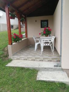 a patio with a table and chairs and flowers at Apartman Panorama in Mokra Gora