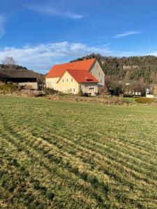 een huis met een rood dak in een veld bij Landhaus Böhmer, Ferienhaus Schrammsteinblick in Kurort Gohrisch