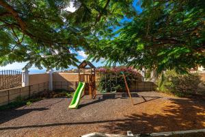 um parque infantil com um baloiço num quintal em Villa Aurora with Heated Pool em La Cisnera