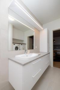 Baño blanco con lavabo y espejo en Modern flat in Reykjavík, Úlfarsárdalur, en Reikiavik