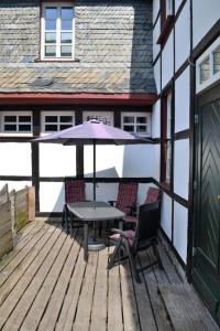 une terrasse avec une table, des chaises et un parasol dans l'établissement Villa Rur, à Monschau