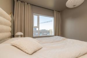 1 dormitorio con cama blanca y ventana en Modern flat in Reykjavík, Úlfarsárdalur, en Reikiavik