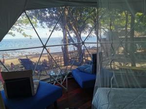 a room with a view of the beach from a tent at Glamping Dome Dauin Beach and Dive Resort in Dauin