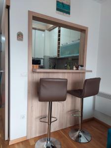 uma cozinha com um bar com duas cadeiras e um espelho em Nice apartment near Old Town and sea em Budva