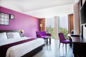 Habitación de hotel con cama y pared púrpura en Grand Edge Hotel Semarang - CHSE Certified en Semarang